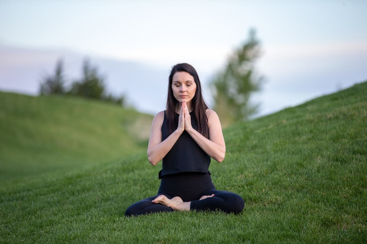 People practising yoga on the grass in a sunlit city park.